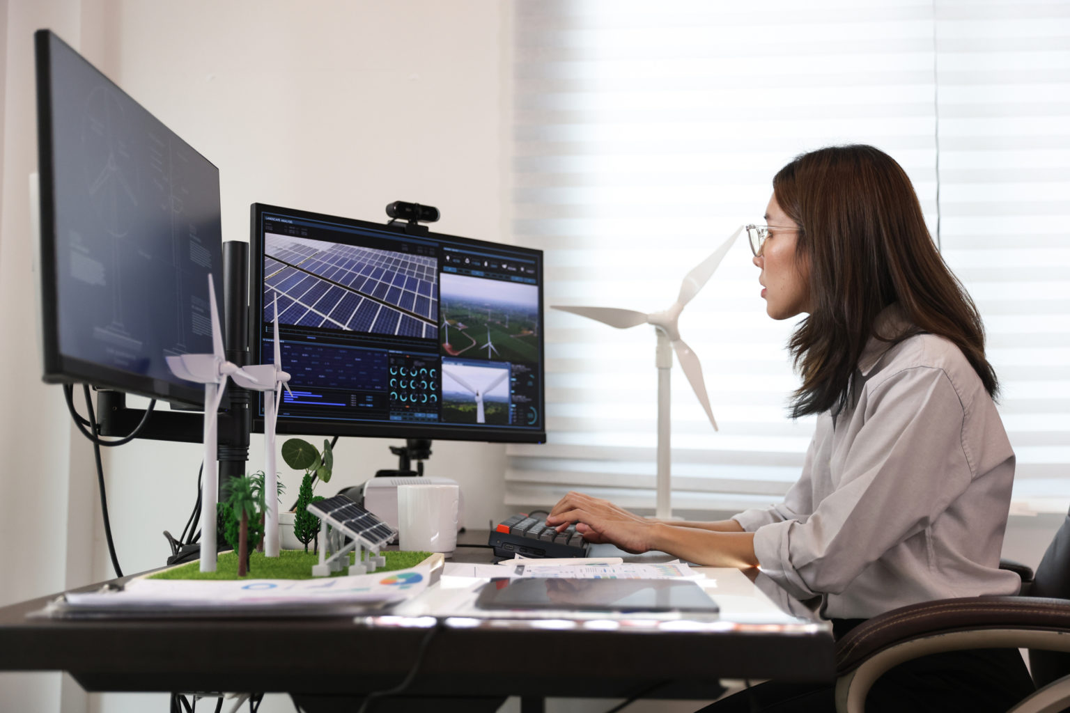 Portrait Beautiful Asian woman work on computer with model of wind turbine and Solar panel.